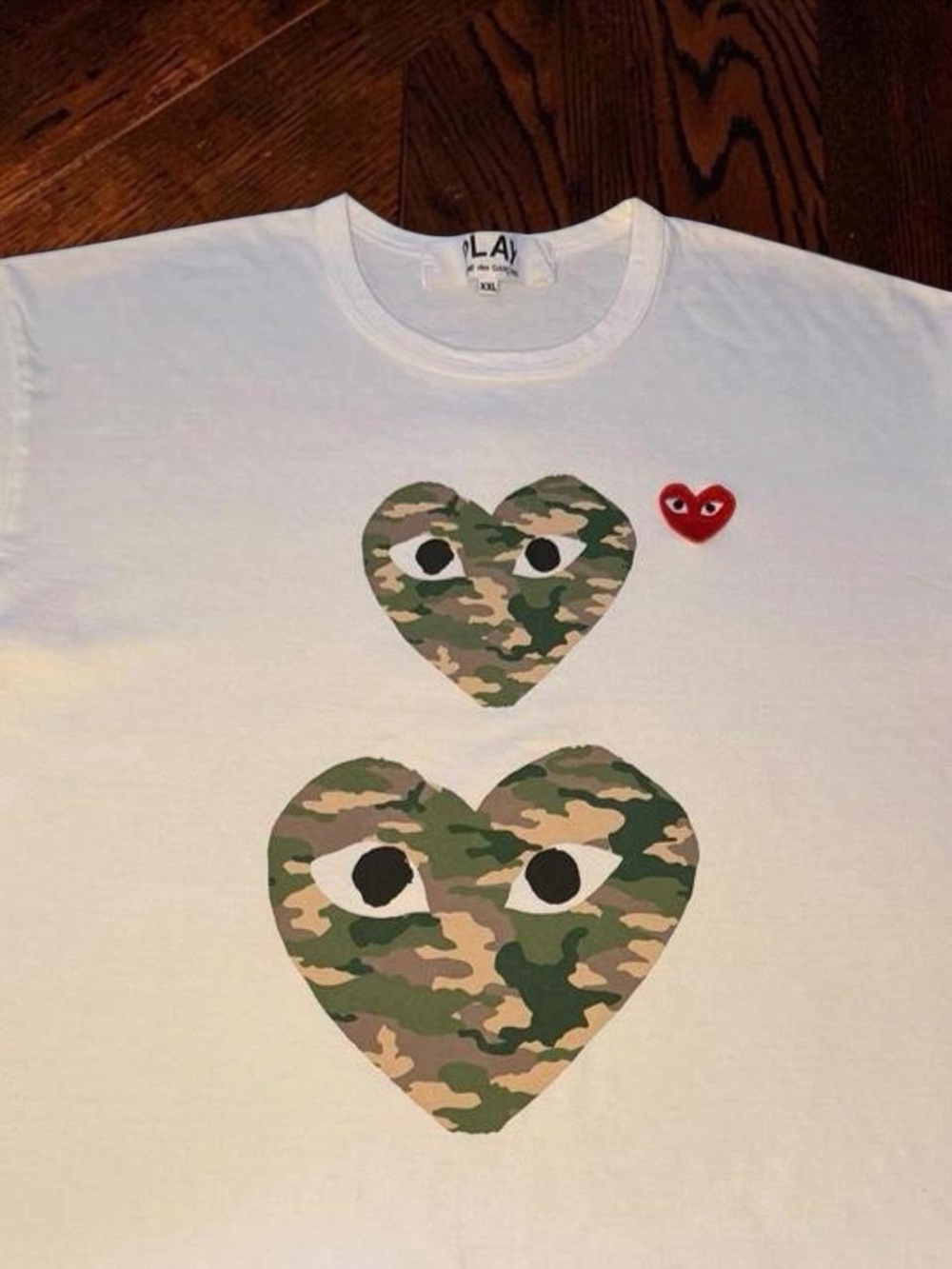 Comme des Garcons men’s White Tee with Camo Heart Motifs and Red Heart Patch